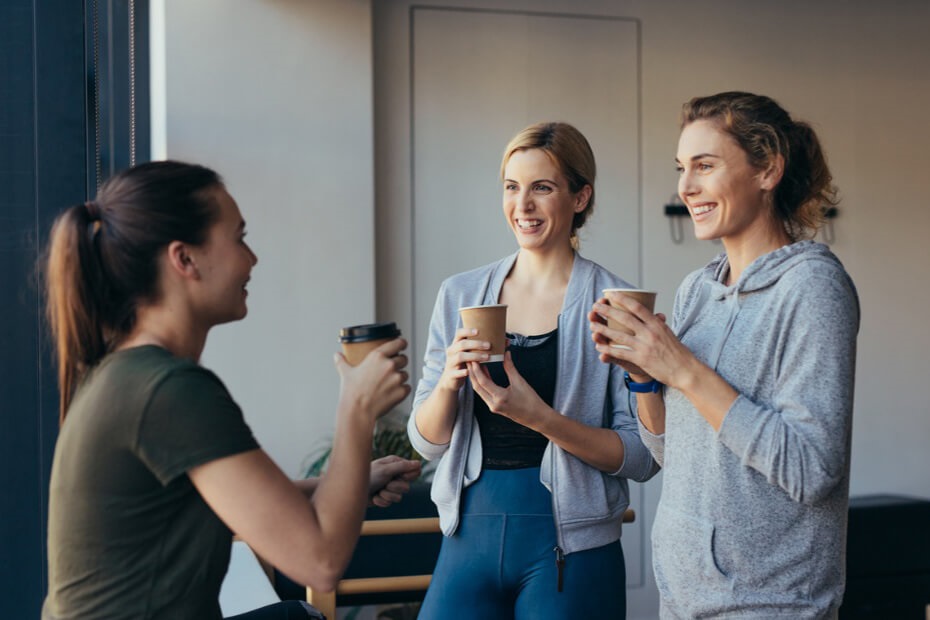 A photo of three people chatting with takeaway coffee cups in their hands.