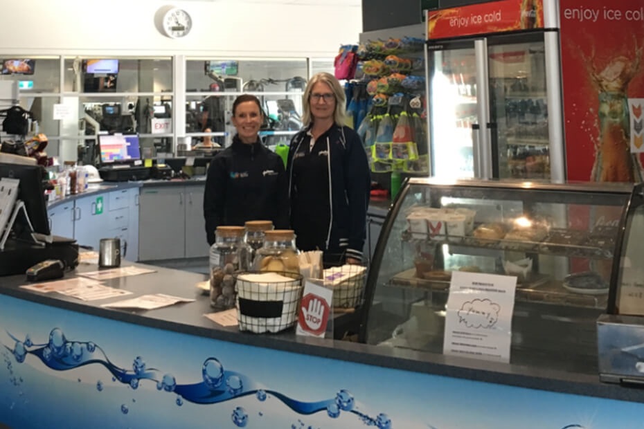 A photo of the staff at the Whale Tale cafe counter smiling at the camera.