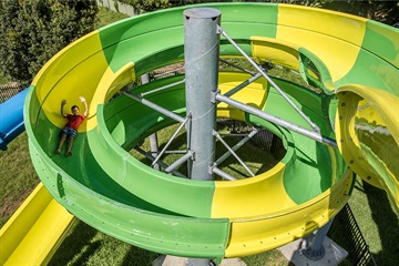 A photo of a child sliding down a large outdoor spiral slide.