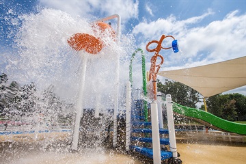 A photo of a playground with a large spray of water coming out of some of the playground equipment.