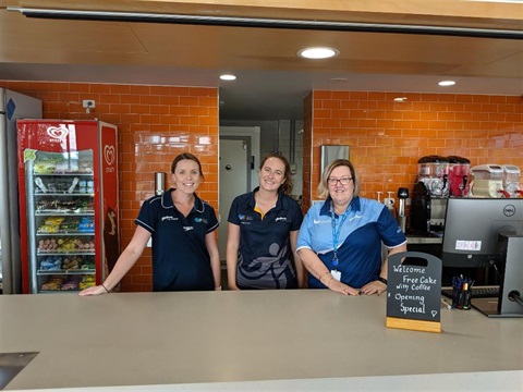 A photo of the staff at the courtside cafe counter smiling at the camera.