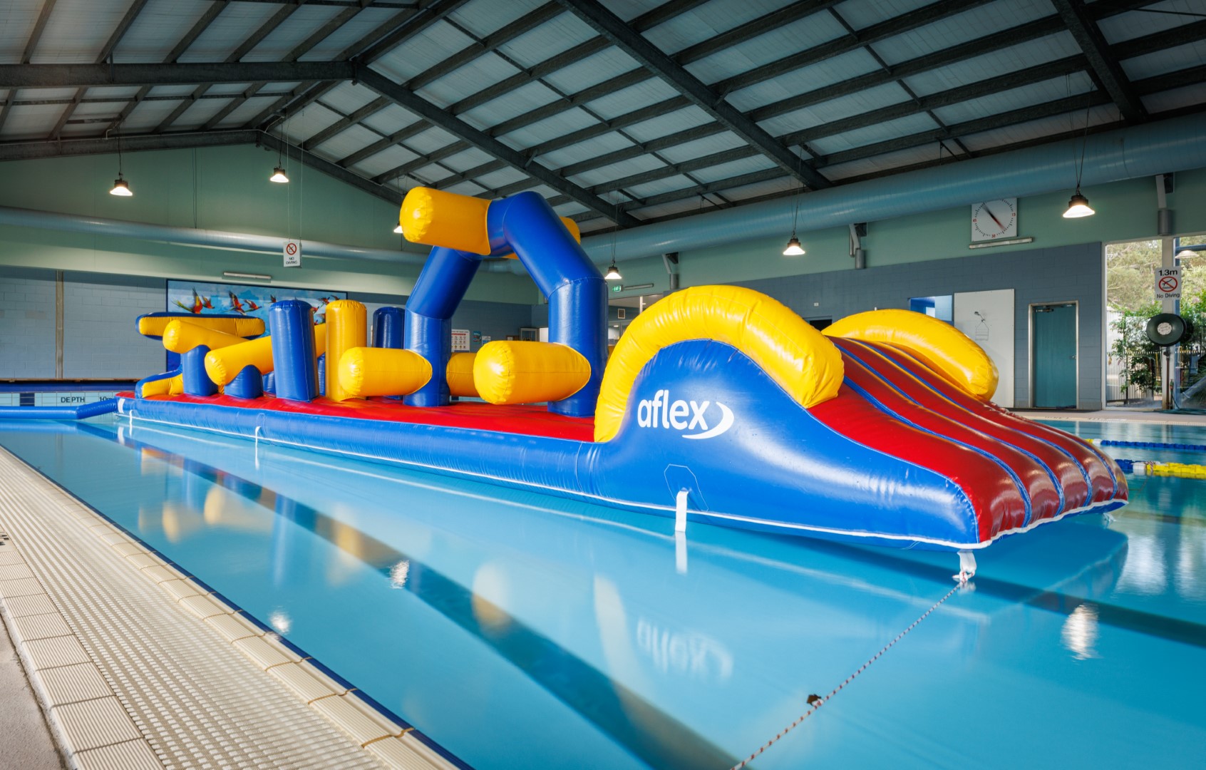 A photo of an inflatable obstacle course floating in the water of an indoor pool.